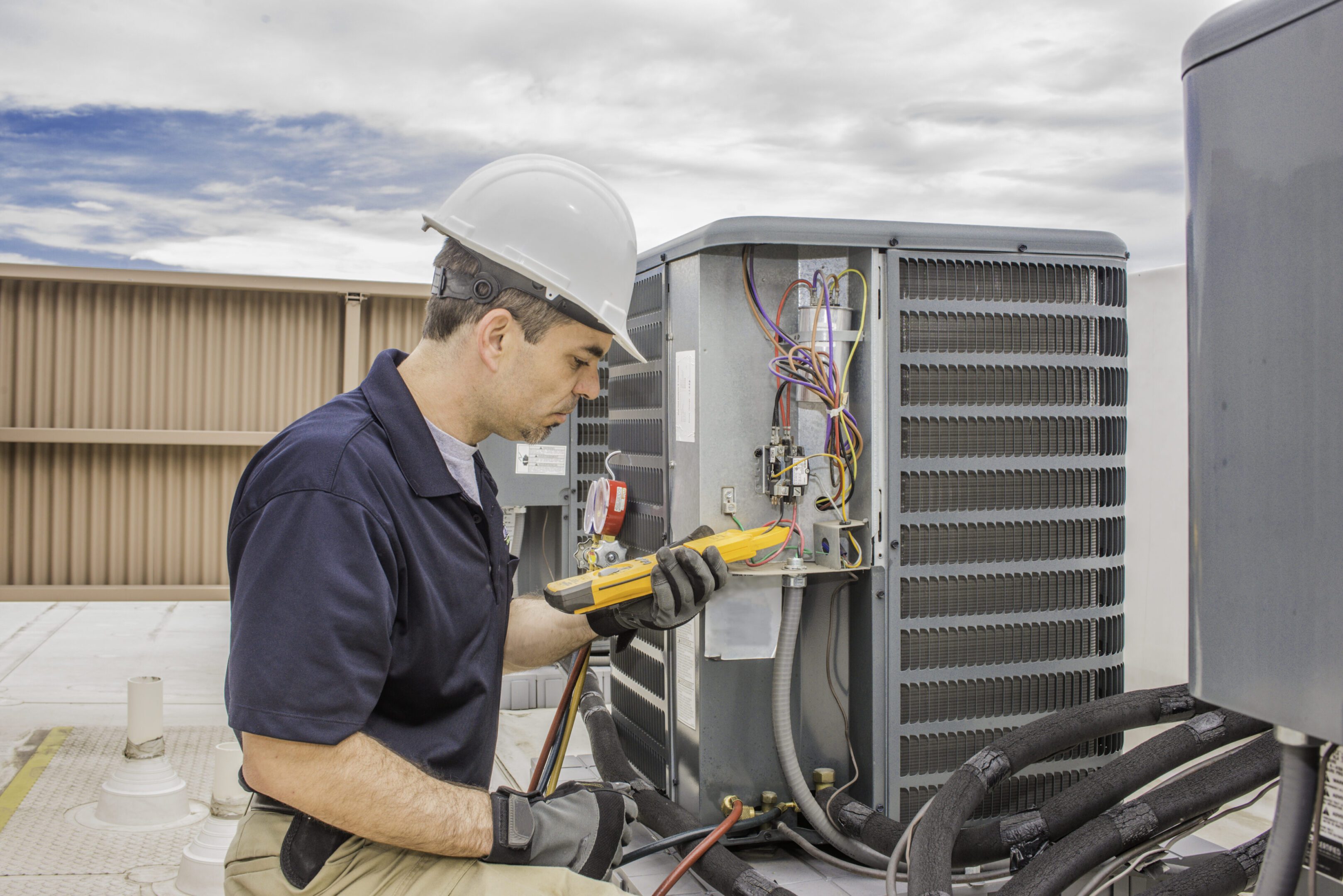 Technician inspecting rooftop HVAC unit.