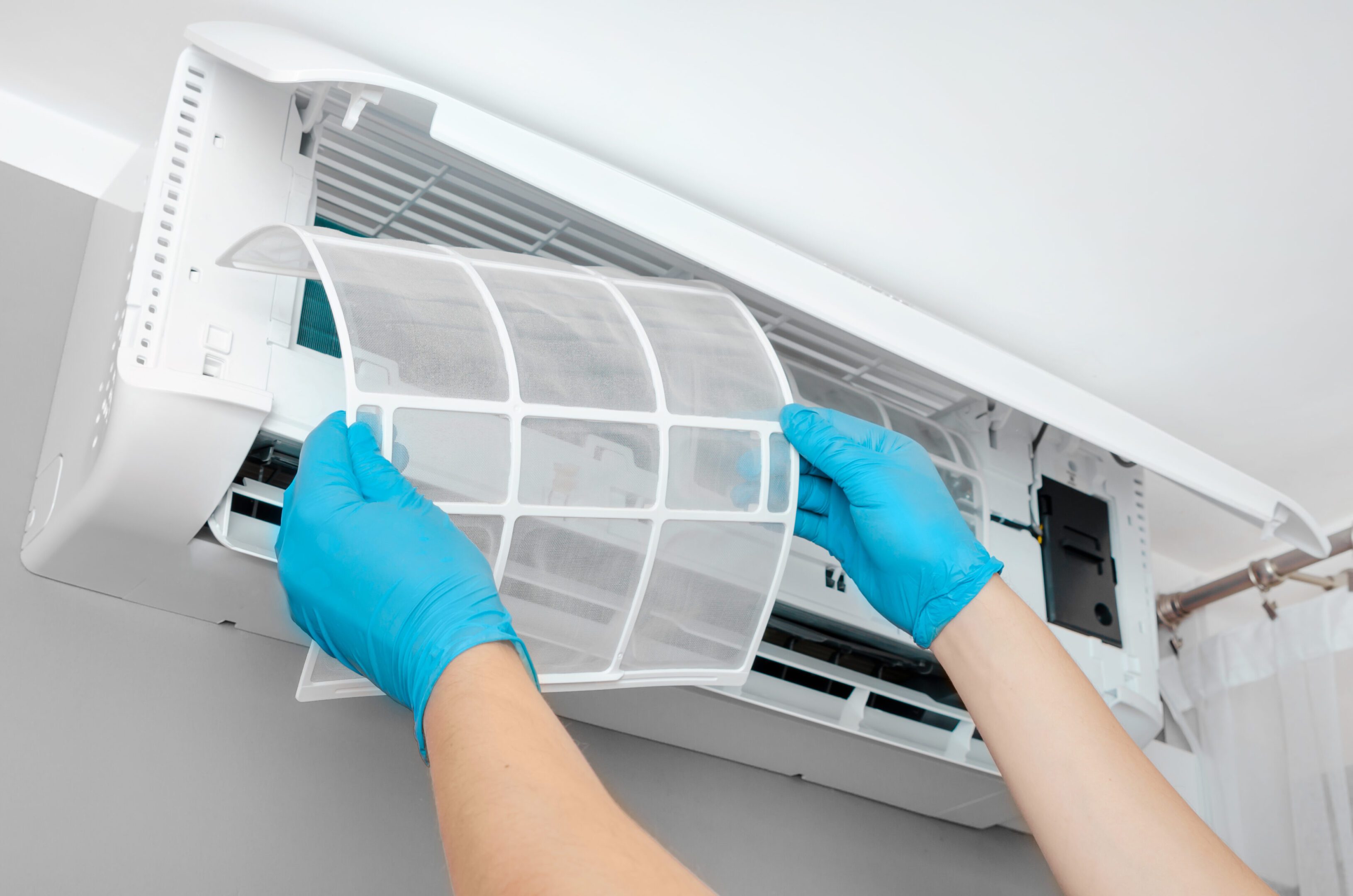 Cleaning air conditioner filter with gloves.